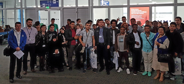 20 avril 2016 à l'aéroport d'Athènes, en salle d'embarquement : groupe de réfugiés au départ pour Paris, accompagnés par Lola GIRARD, ODL relocalisation (à gauche), Nicolas CARAPLIS, ODL-I du SSI et les représentants de l'OIM. - PNG